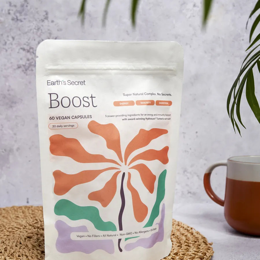 Earth’s Secret Boost pouch on a woven mat beside a mug