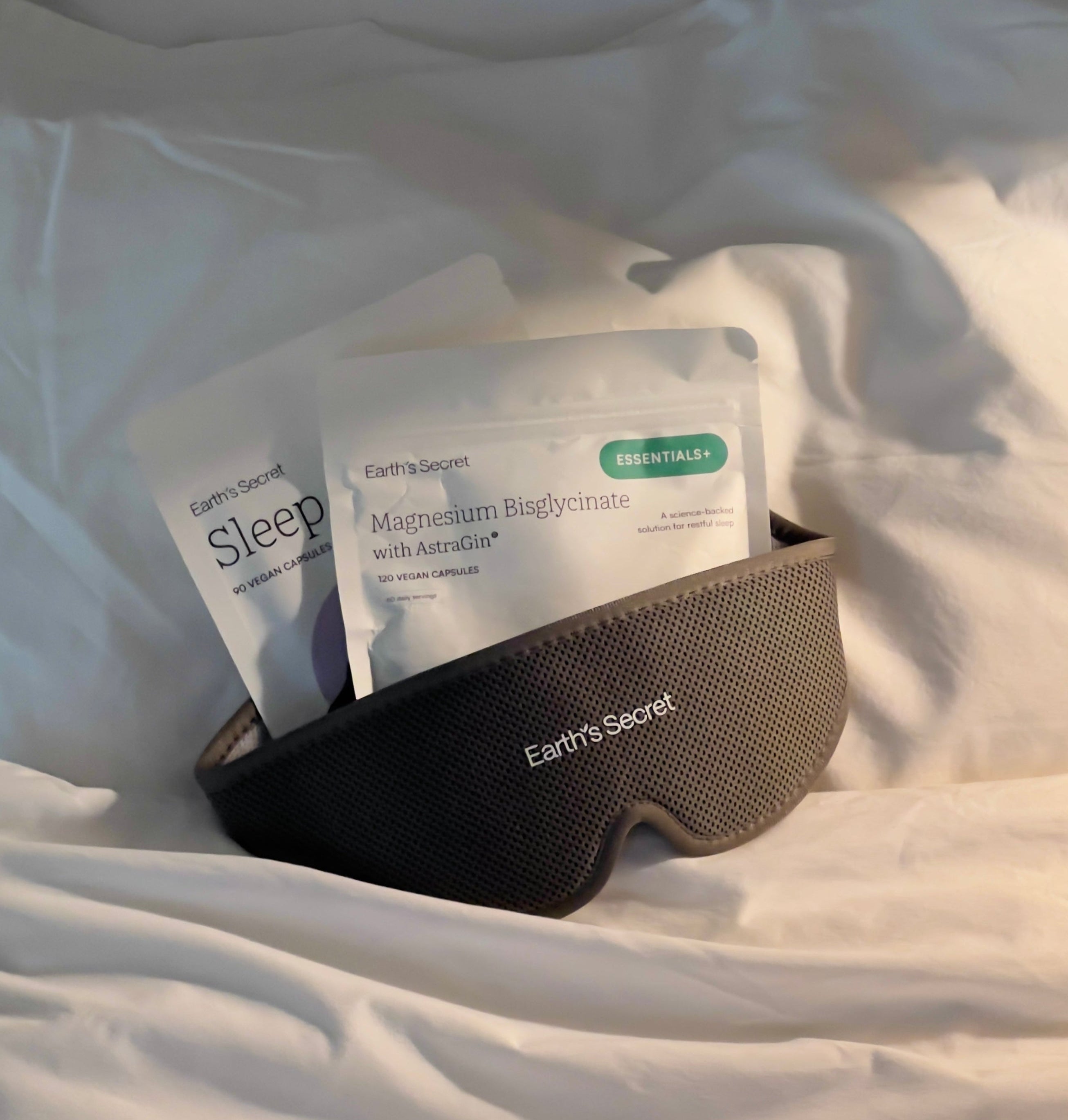 Sleep mask and Earth's Secret sleep products on a white pillow