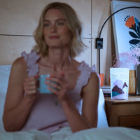Woman sitting on a bed holding a mug with a blurred background